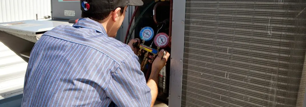 HVAC technician servicing a condenser unit in Statesboro